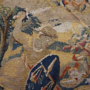 Detail of a ribbed, low-pile textile pattern featuring blue, yellow, beige, green, and red hues.