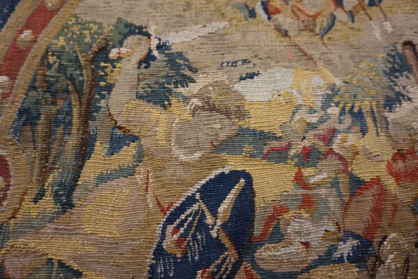 Detail of a ribbed, low-pile textile pattern featuring blue, yellow, beige, green, and red hues.