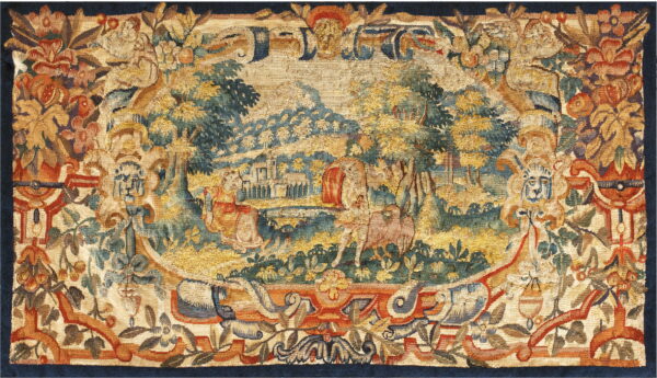 This low-pile tapestry features a gold, teal, and rust landscape vignette surrounded by an ornate floral border.