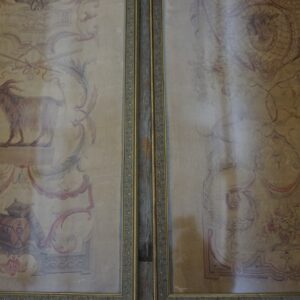 Two framed tapestry panels show faded pastoral scenes, including a goat and floral scrolls, against a tan background.