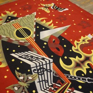 Red flatweave rug featuring abstract musical and geometric designs in black, yellow, and white on wood flooring.