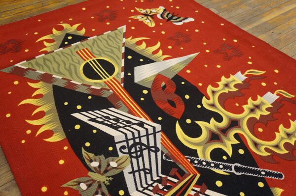 Red flatweave rug featuring abstract musical and geometric designs in black, yellow, and white on wood flooring.