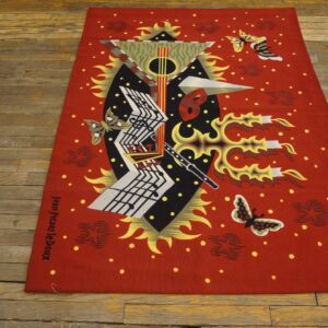 Red abstract rug with geometric musical notation, butterflies, and artist signature on aged wood floor.