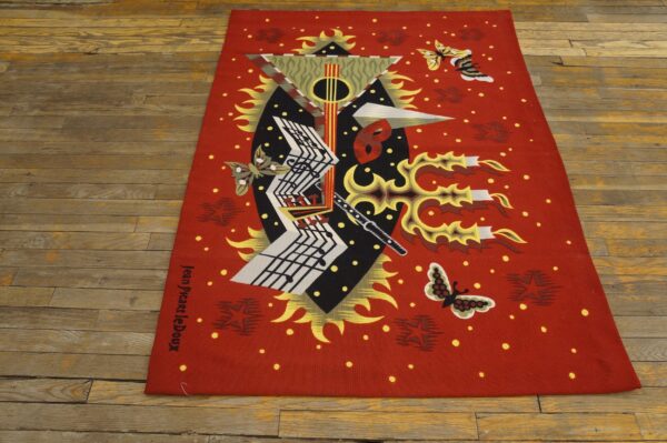 Red abstract rug with geometric musical notation, butterflies, and artist signature on aged wood floor.