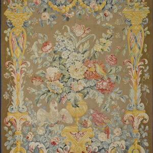 A low-pile rug with a taupe field features a floral bouquet, birds, and ornate yellow scrollwork in pink and blue accents.