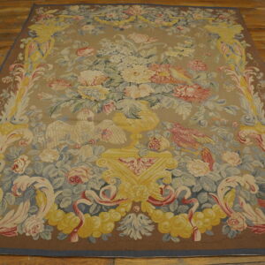 Detailed taupe rug with a yellow urn, pink flowers, and birds centered on a wooden floor.