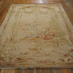 Faded beige, pink, and green tapestry rug displaying a large neoclassical scene on wood planks.