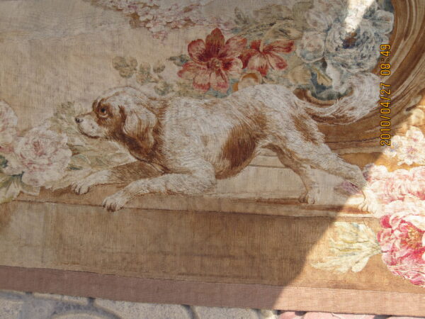 Low-pile rug with a detailed tapestry design of a brown dog and red, pink, and blue florals.