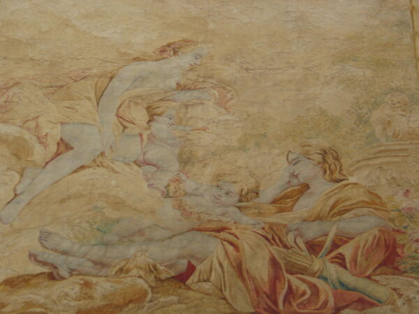 Pictorial rug displaying a reclining classical scene using muted tan, gold, blue, and red tones.