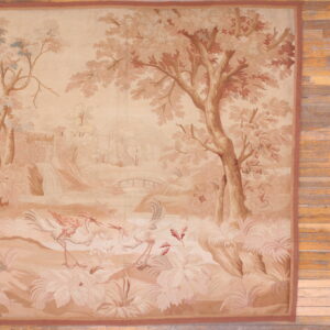 Beige and brown low-pile rug displaying a scenic pastoral pattern with trees and two stylized birds on wood flooring.