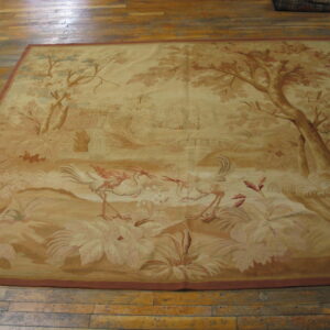 Beige pictorial rug depicting trees, a waterfall, and two large wading birds on wood flooring.