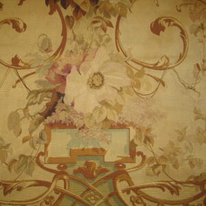 Tapestry-style rug detail featuring a large floral bouquet and brown ornamental scrollwork on a beige ground.