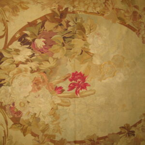 Ornate low-pile rug featuring a large gold medallion bordered by scrolling leaves and faded floral bouquets.