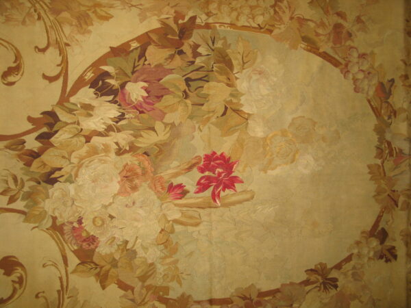 Ornate low-pile rug featuring a large gold medallion bordered by scrolling leaves and faded floral bouquets.