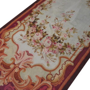 Low-pile runner featuring pink floral sprays on a light blue ground surrounded by a detailed burgundy border.
