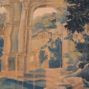 Woven textile with a landscape pattern of beige arches, dark blue foliage, and tan hills.