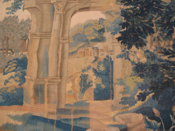 Woven textile with a landscape pattern of beige arches, dark blue foliage, and tan hills.