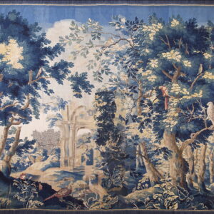 Woven tapestry with a detailed forest scene in blues, tans, and browns featuring birds and ruins.