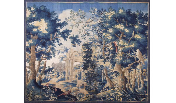 Woven tapestry with a detailed forest scene in blues, tans, and browns featuring birds and ruins.