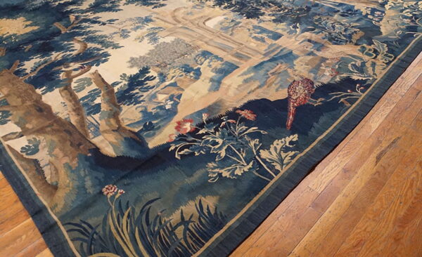 Low-pile rug with detailed blue and tan forest tapestry design resting on wooden flooring.