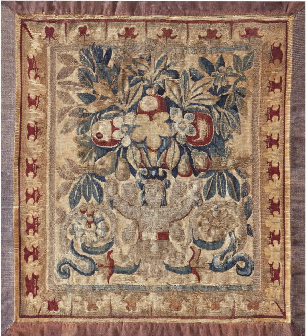 Flat-woven square textile with a beige ground, depicting blue leaves, red fruit, and a maroon animal border.