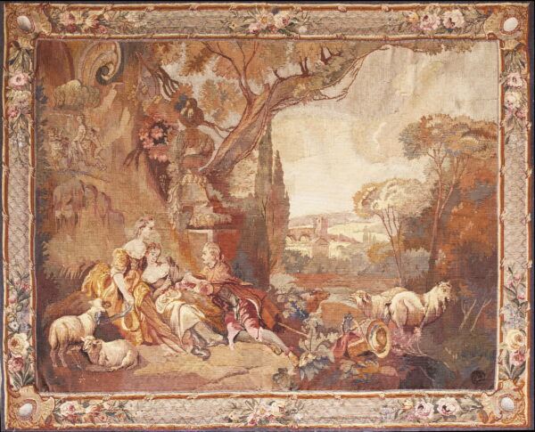 Tan and brown tapestry rug displaying a classical landscape scene surrounded by a wide floral border.