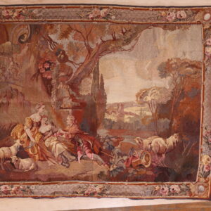Low pile rug displaying a pastoral landscape scene with figures, trees, sheep, and a floral edge.