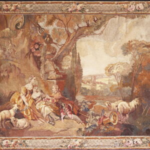 Tapestry rug featuring a pastoral scene with figures and sheep framed by a floral border in muted earth tones.