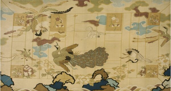 Pale yellow rug with an ornate design of birds, clouds, and flowers using green, blue, and earthy brown colors.