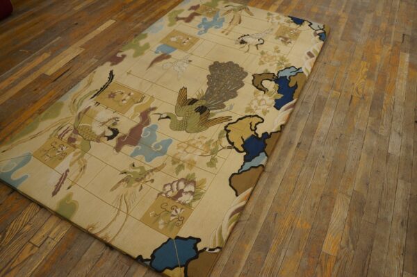 A low pile tan rug with an elaborate peacock and bird pattern lies on distressed wood flooring.