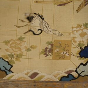 Low-pile beige rug patterned with a stylized crane, flowers, and peacock feathers on rustic wood floor.