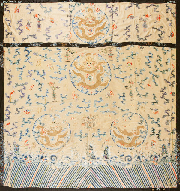 Cream embroidered textile displaying central gold dragon motifs, blue cloud scrolls, and a border of multicolored diagonal stripes.