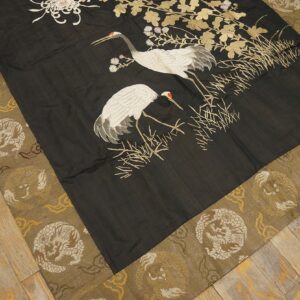 Black flat rug with white crane motif and gold leaves, surrounded by a dragon-patterned khaki border.