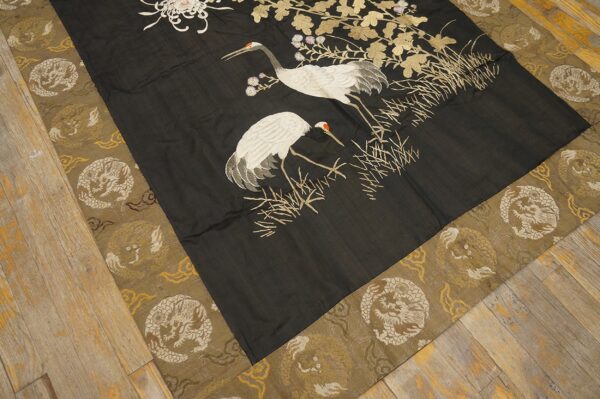 Black flat rug with white crane motif and gold leaves, surrounded by a dragon-patterned khaki border.