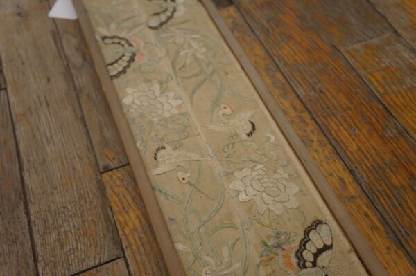 Narrow, pale runner with detailed floral and bird patterns, including white cranes, on distressed wood flooring.