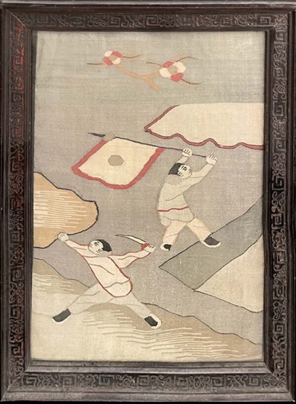 Framed tapestry in grays, tan, and red depicting two figures against an abstract background within a carved wood frame.
