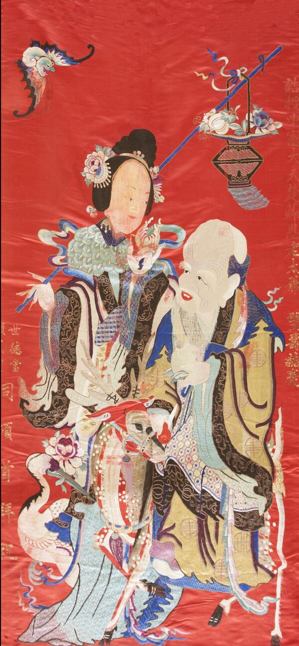 Detailed traditional rug pattern of two figures and motifs in gold, blue, and white on a bright red field.