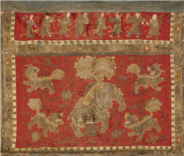Red embroidered textile displaying gray and gold mythical beasts, bordered by dancing figures and floral motifs.