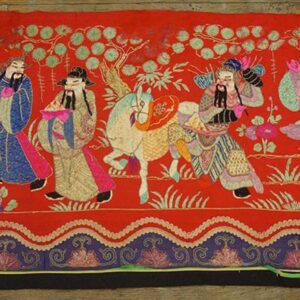 A red textile runner featuring multicolored figural scenes, foliage, and a patterned blue and scalloped border.