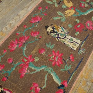 Figurative textile runner with magenta and teal floral embroidery lies on distressed gray wood flooring.
