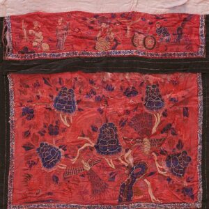 Red embroidered textile featuring blue floral designs, stylized birds, and figural scenes, framed by black borders.