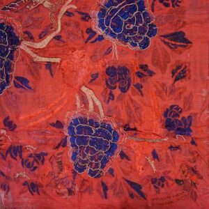 Highly textured red textile fragment featuring large blue flowers and intricate gold embroidered details.