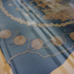 Detailed view of a low-pile navy textile featuring thick, coiled gold cord applique designs.