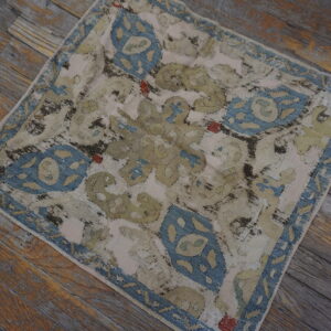 Distressed blue, beige, and olive patterned rug lying on rustic gray wooden planks.
