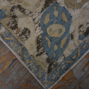 Heavily textured low-pile rug in blue, beige, and dark brown patchwork lies on rustic wood flooring.