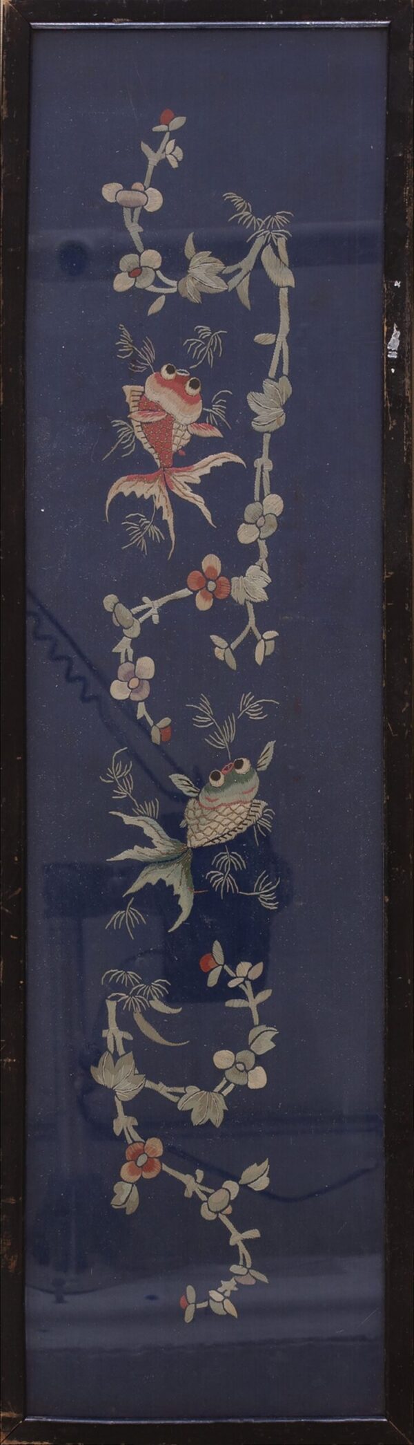 Framed navy blue textile embroidered with vertical vines, pale flowers, and two colorful goldfish.