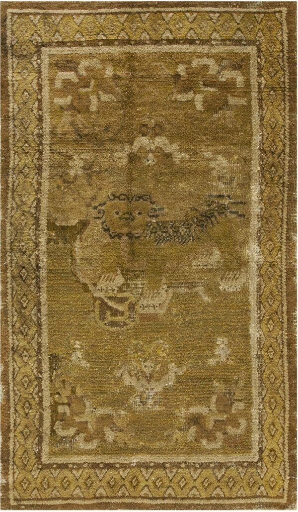 A heavily worn rug displaying olive and brown tones with a central animal motif and diamond borders.