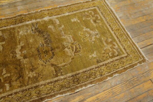 Distressed, low-pile runner rug with faded medallion and geometric borders on rustic wooden plank flooring.