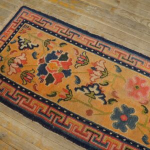 Golden orange runner rug featuring multicolored floral motifs and a detailed geometric border on wood flooring.
