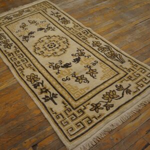 Beige runner rug with brown and yellow traditional motifs and fringe on distressed wood flooring.